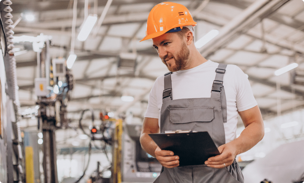 man in werkkleding die een veiligheidshelm op heeft en iets controleert